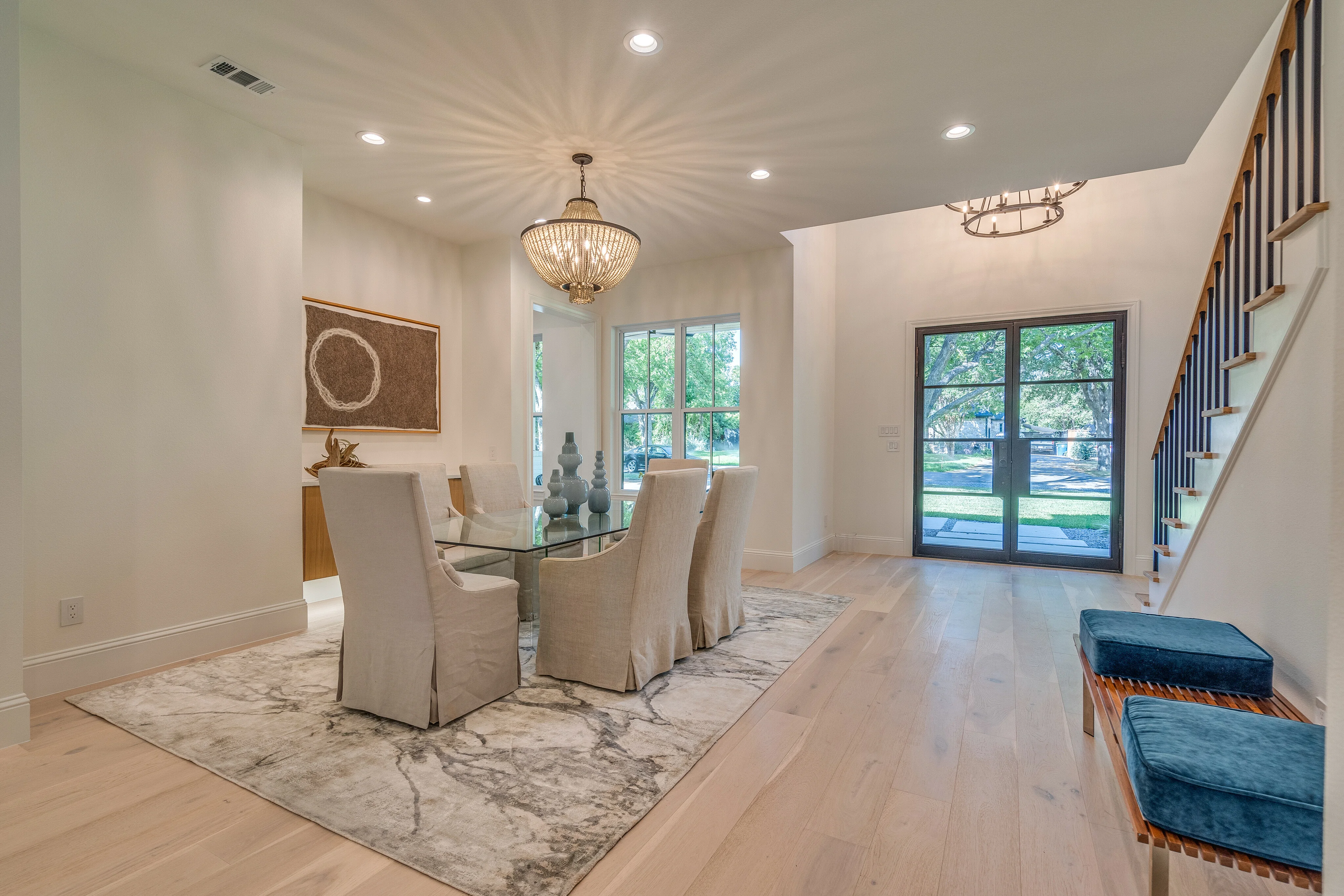 Dining room with sculptural lighting, black-framed front doors, and the main staircase