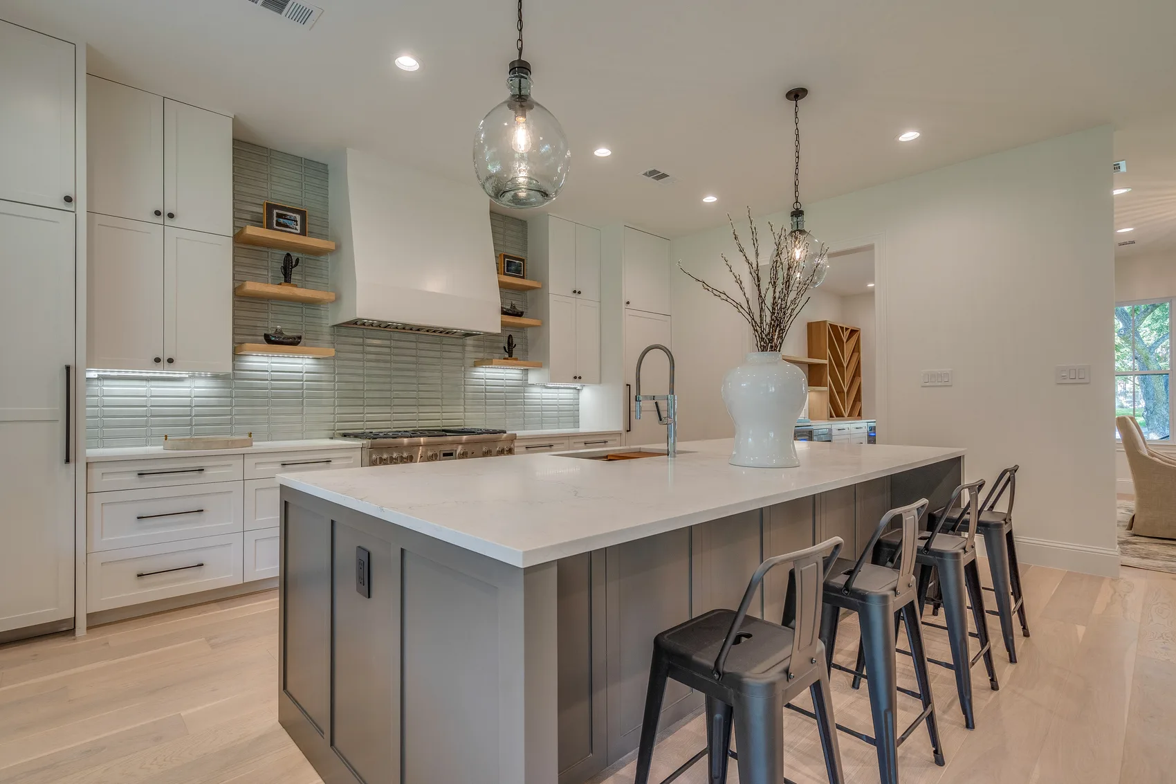 Kitchen island with seating, pendant lights, full-height cabinetry, and range wall
