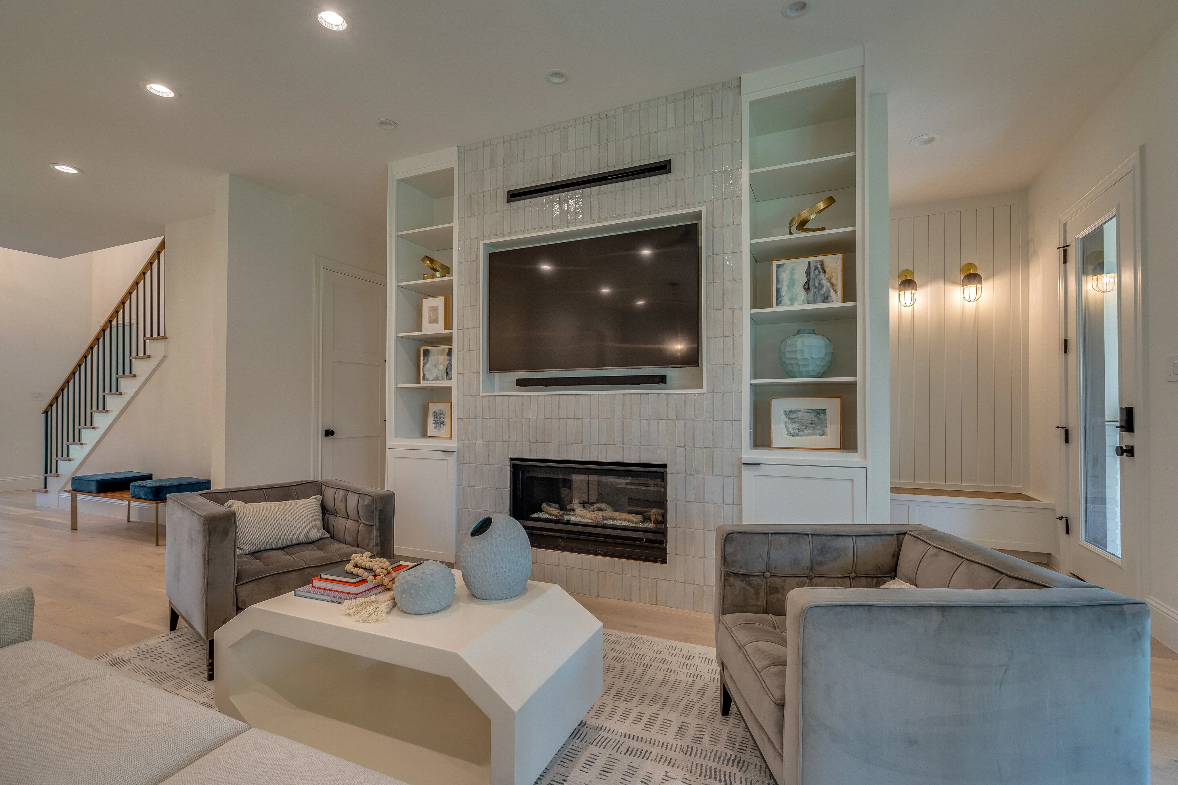 Open living room with fireplace, built-in shelving, pale wood floors, and adjacent dining area