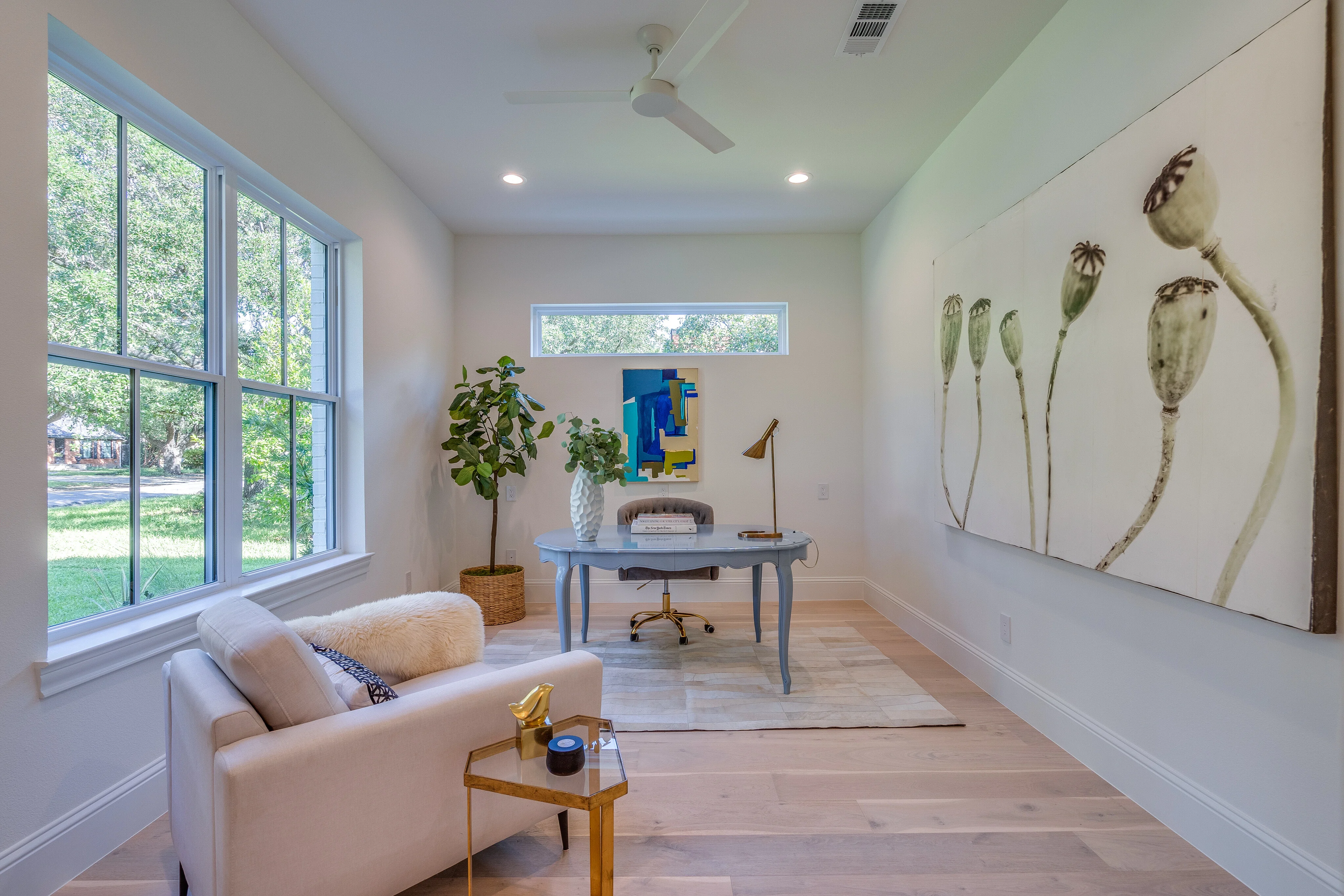 Light-filled office with corner windows, pale wood floors, and a long built-in work surface