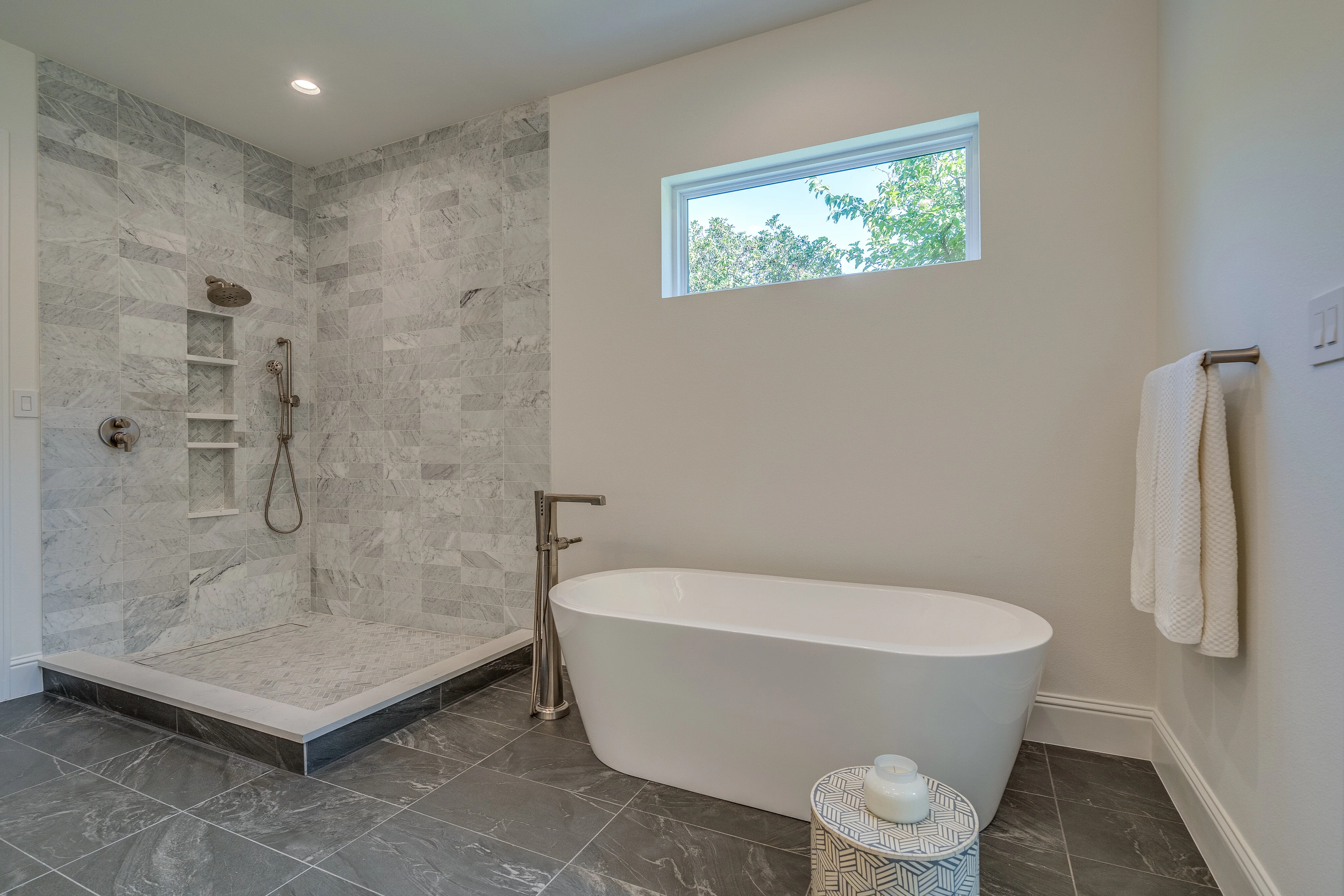 Primary bathroom with a freestanding tub, large stone shower, and clerestory window
